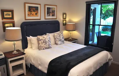 a bedroom with a bed with two lamps and a window at Blueberry Hill Cottages in Franschhoek