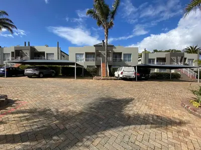 a parking lot in front of a house with a palm tree at Durbanville Self Catering Apartments in Cape Town