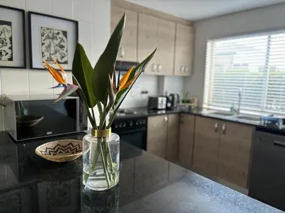 a vase with flowers on a counter in a kitchen at Durbanville Self Catering Apartments in Cape Town