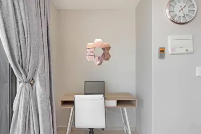 a room with a desk with a computer and a clock at Modern 3 Bed Apartment Blouberg in Cape Town