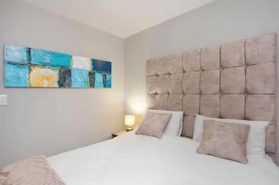 a bedroom with a white bed with a large headboard at Modern 3 Bed Apartment Blouberg in Cape Town