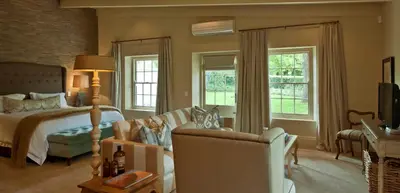 a bedroom with a bed and a couch and a chair at La Clé Village in Franschhoek