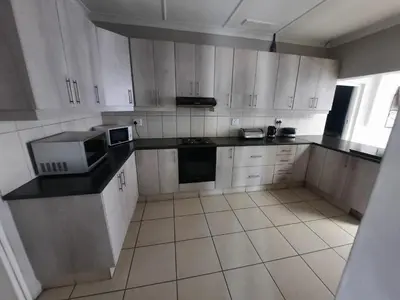 a kitchen with white cabinets and black counter tops at GALAXY BOSTON BELLVILLE in Cape Town