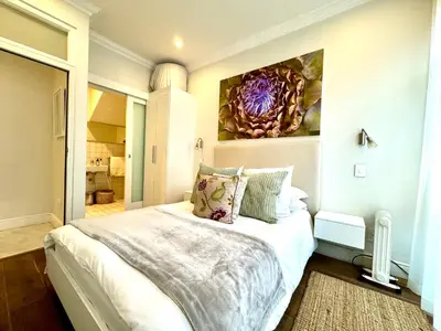 a bedroom with a bed with a painting on the wall at Tuishuisie in Stellenbosch
