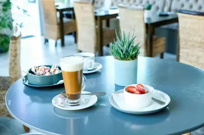 a table with a cup of beer and a bowl of strawberries at Ocean Breeze Hotel in Strand