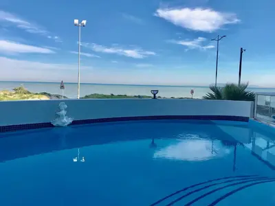 a swimming pool with a view of the ocean at Ocean Breeze Hotel in Strand