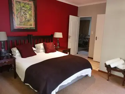 a bedroom with a large bed with red walls at Mooring House in Somerset West
