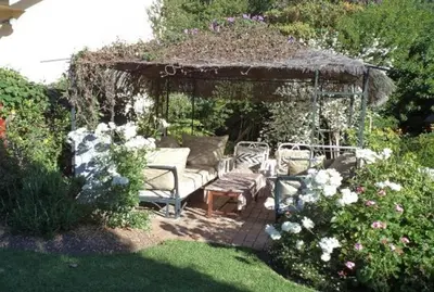 a gazebo with two chairs and a bench in a garden at Mooring House in Somerset West