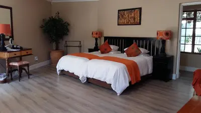a bedroom with a large bed with orange and white sheets at Mooring House in Somerset West