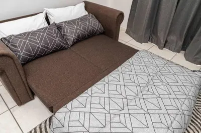 a couch with two pillows on top of a rug at Century On Lake Apartment in Cape Town
