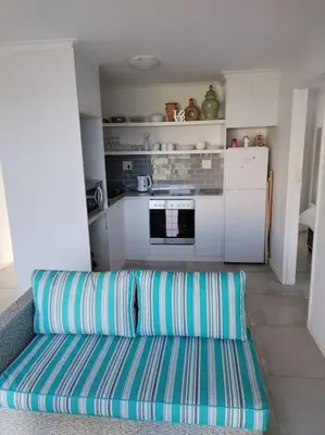 a living room with a couch and a kitchen at MarineView Getaway in Hermanus