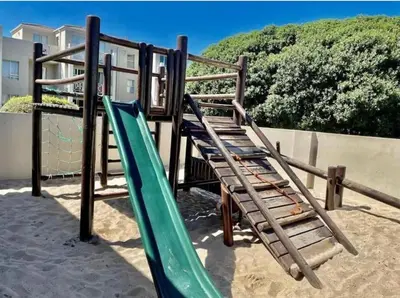 a playground with two slides in the sand at MarineView Getaway in Hermanus