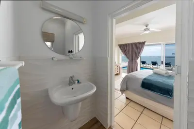 a bathroom with a sink and a bed and a mirror at 'Harbour Views' - 2 bedroom, sleeps 4 with private pool and large veranda! in Gordonʼs Bay