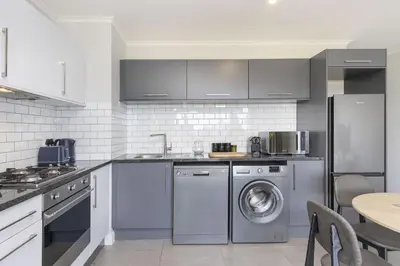 a kitchen with a washer and dryer in it at The Terraces 330 by Host Agents in Cape Town