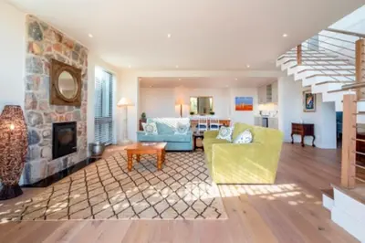 a living room with a stone fireplace and a yellow couch at Grandeur in Hermanus