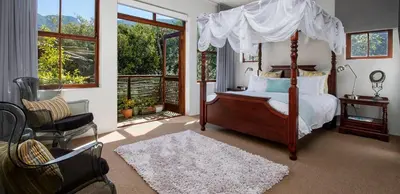 a bedroom with a canopy bed and a chair at Two Bedroom Soutpan Apartment in Hermanus