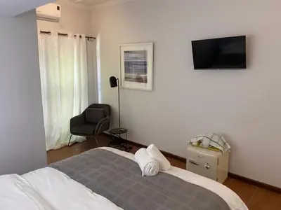 a bedroom with a bed and a chair and a television at 3 on The Fairway Pinelands in Cape Town