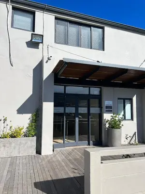 a building with glass doors and a bench in front at Hermanus Waterfront Apartment no 17 in Hermanus