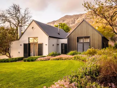 a white house with a black roof and a green yard at Farm Keerweer in Stellenbosch