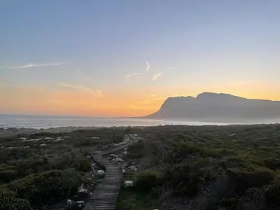 a sunset over the ocean with a mountain in the distance at Views galore in Kleinmond in Kleinmond