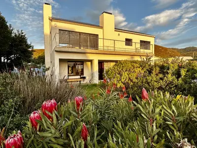 a house with a flower garden in front of it at Happy Place Pringle Bay in Pringle Bay