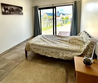a bedroom with a bed and a large window at Happy Place Pringle Bay in Pringle Bay