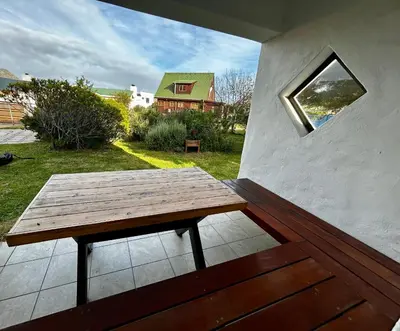 a wooden picnic table on a patio with a window at Happy Place Pringle Bay in Pringle Bay