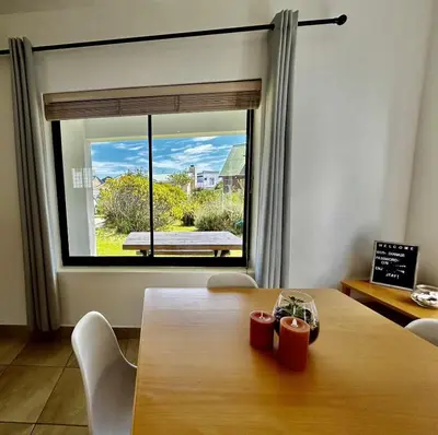 a dining room with a table and a large window at Happy Place Pringle Bay in Pringle Bay