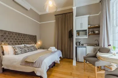 a bedroom with a large bed and a kitchen at Bonne Esperance Studio Apartments in Stellenbosch