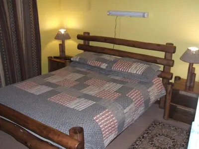a bedroom with a bed with a wooden headboard and two lamps at Pentzhaven Guesthouse in Table View