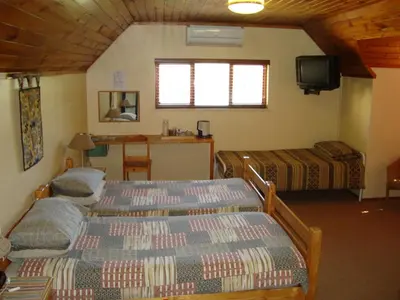 a bedroom with two beds and a tv and a table at Pentzhaven Guesthouse in Table View