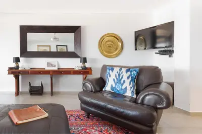 a living room with a leather chair and a mirror at Rocky Bay on the View in Gordonʼs Bay