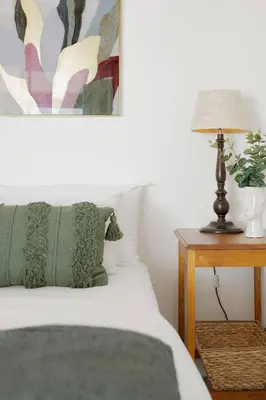 a bedroom with a bed and a table with a lamp at Rocky Bay on the View in Gordonʼs Bay