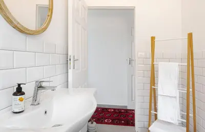 a white bathroom with a sink and a mirror at Rocky Bay on the View in Gordonʼs Bay