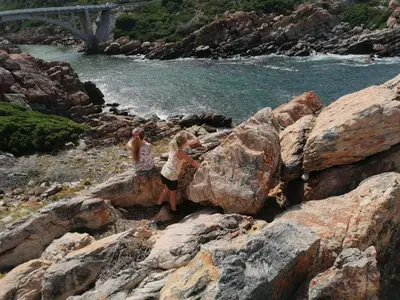 two children are standing on rocks near the water at Rocky Bay on the View in Gordonʼs Bay