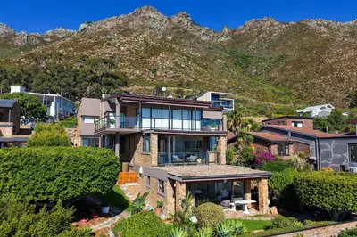 a house with a mountain in the background at Zaria Sun Cottage in Gordonʼs Bay