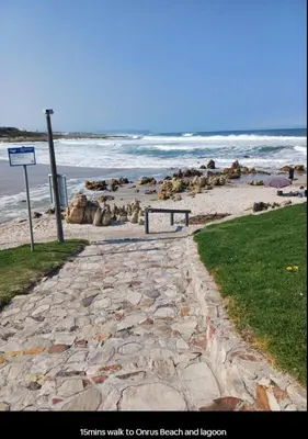 a stone walk way to a beach and the ocean at Dukes Place in Hermanus