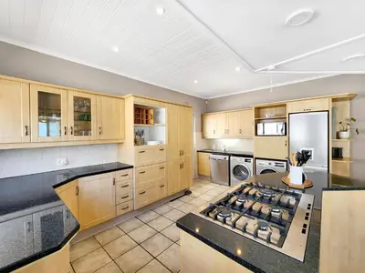 a large kitchen with wooden cabinets and a stove top oven at Strand Boat House in Cape Town