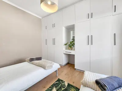 a white bedroom with white cabinets and a couch at Strand Boat House in Cape Town