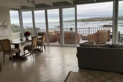 a living room with a couch and a table and chairs at Onrus Sunset Beach House in Hermanus