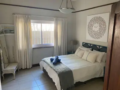a bedroom with a large bed and a window at Onrus Sunset Beach House in Hermanus