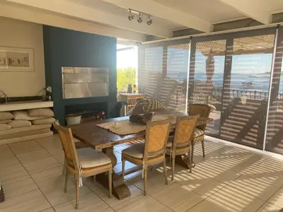 a dining room with a wooden table and chairs at Onrus Sunset Beach House in Hermanus