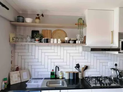 a kitchen with a white and black tile wall at Blouberg Studio in Cape Town
