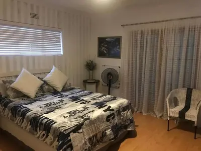 a bedroom with a bed and a chair and a window at 11 on Orange in Cape Town