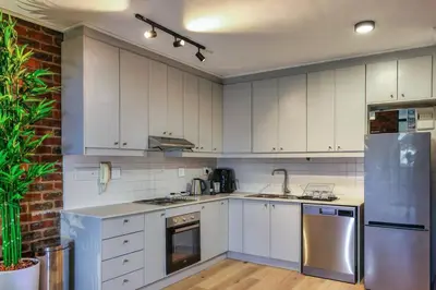 a kitchen with white cabinets and stainless steel appliances at Tranquil Loft Design and Underground Parking in Stellenbosch