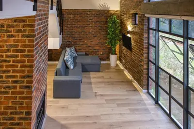 a living room with a couch and a brick wall at Tranquil Loft Design and Underground Parking in Stellenbosch