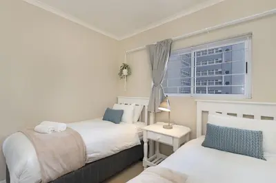 a bedroom with two beds and a window at Portico 405 in Bloubergstrand