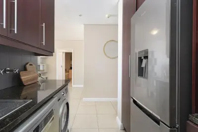 a kitchen with a washer and dryer at Portico 405 in Bloubergstrand