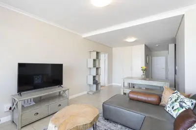 a living room with a couch and a flat screen tv at Portico 405 in Bloubergstrand