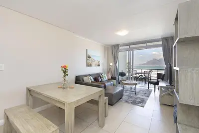 a living room with a couch and a table at Portico 405 in Bloubergstrand